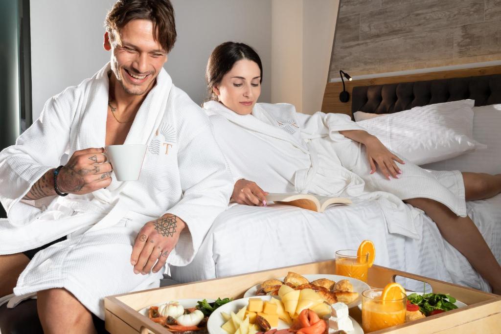a man and woman sitting in bed with a tray of food at Akti Toroni Boutique Hotel in Toroni