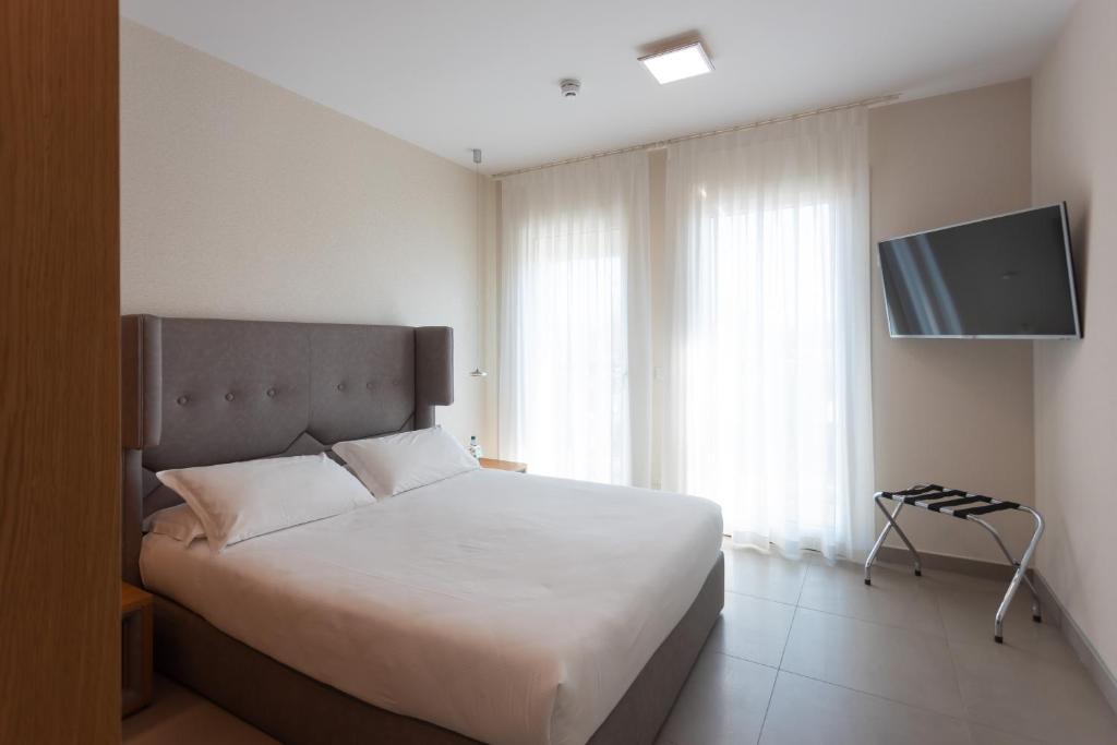 a bedroom with a bed and a flat screen tv at Mosella Suite Hotel in Sottomarina