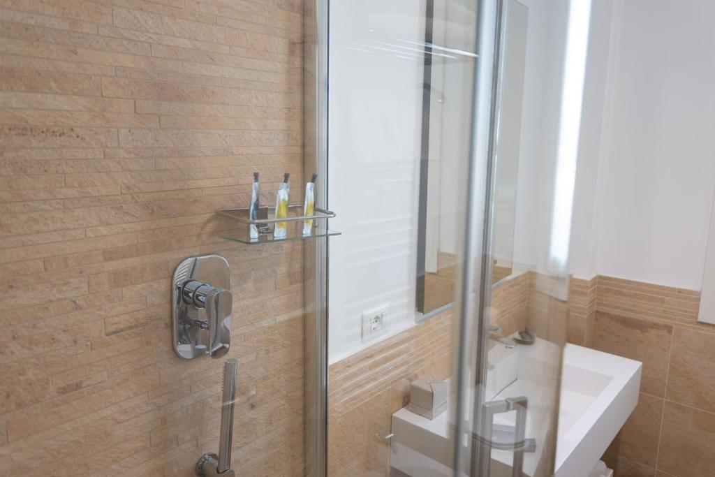 a bathroom with a shower with a sink and a mirror at Mosella Suite Hotel in Sottomarina