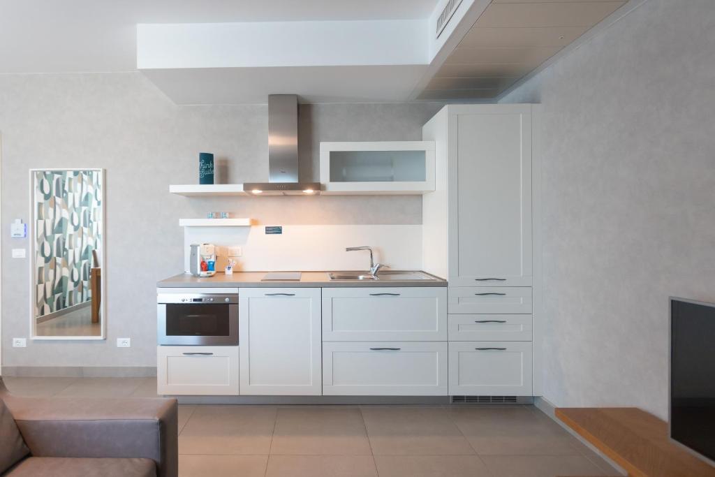 a kitchen with white cabinets and a sink at Mosella Suite Hotel in Sottomarina