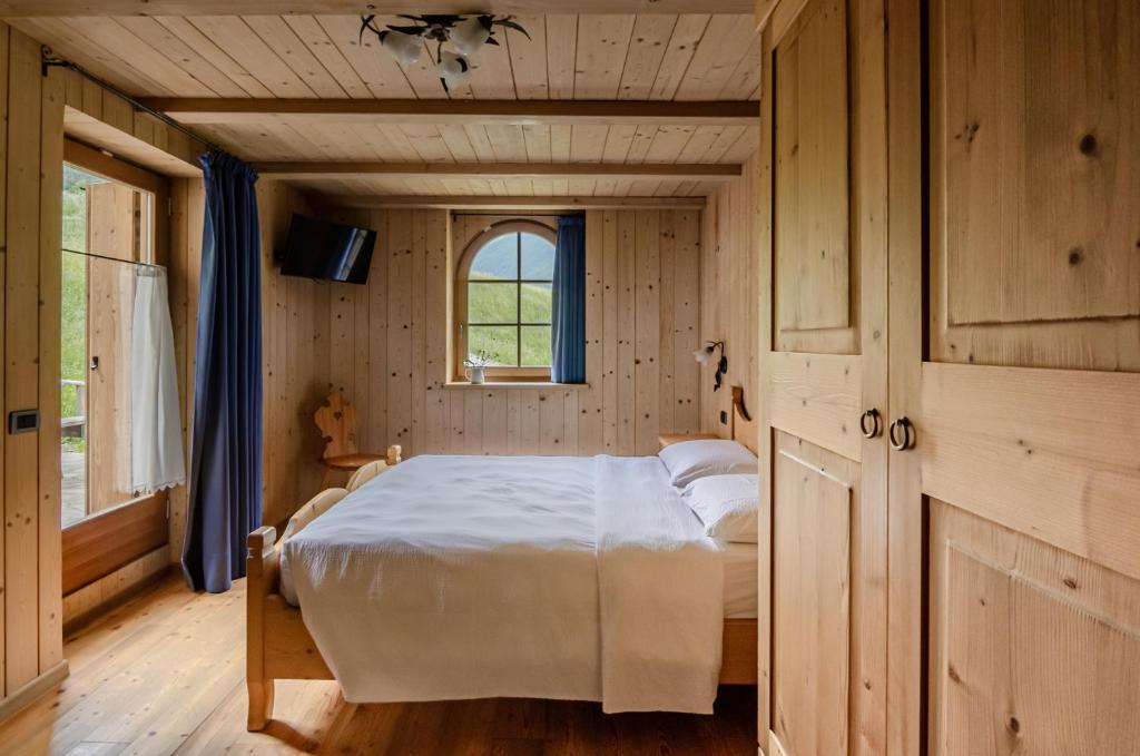 ラッビにあるHotel Chalet val di Rabbiの木製の部屋にベッド1台が備わるベッドルーム1室があります。