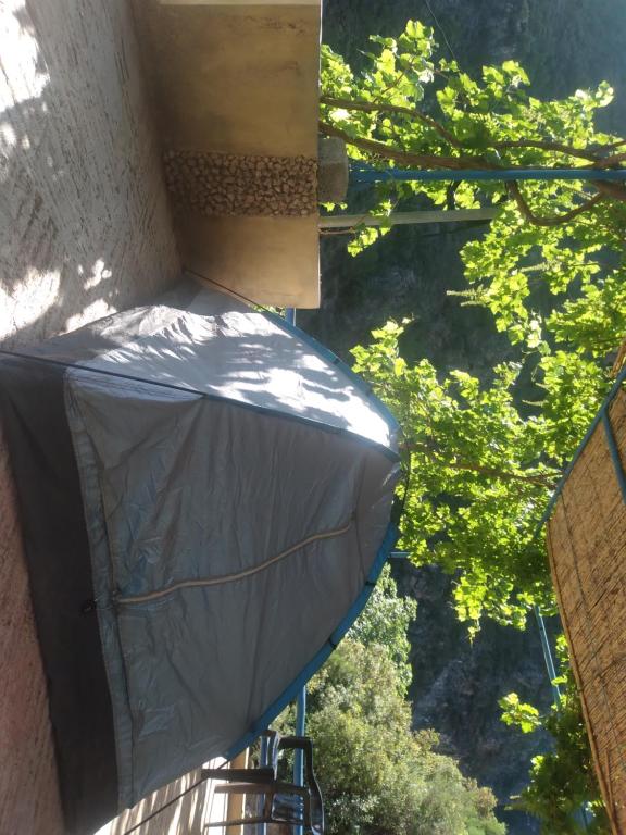 ein grauer Regenschirm auf der Seite eines Gebäudes mit Bäumen in der Unterkunft Le pont de Dieu in Akchour