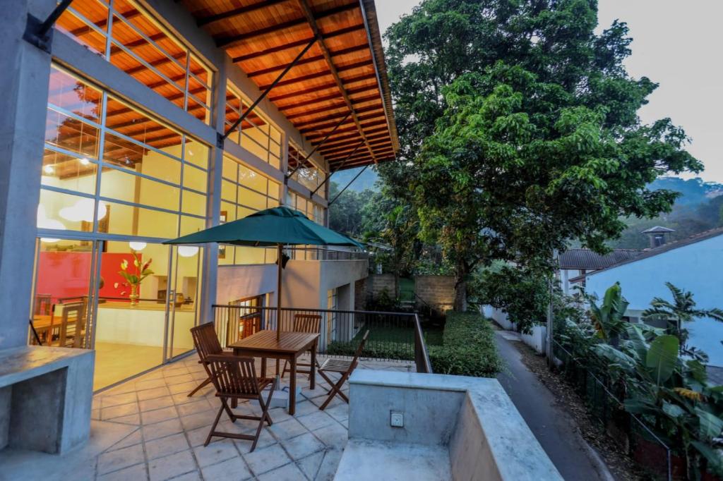 un patio con sillas y una mesa con sombrilla en Margossa Residence by 55TG en Kandy