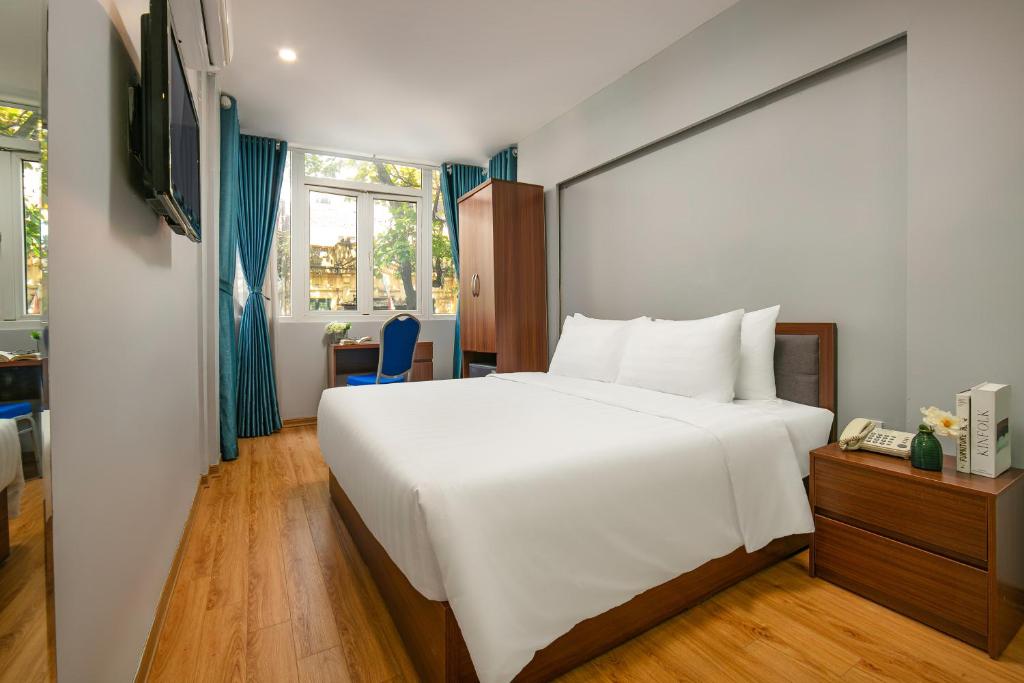 a bedroom with a large white bed and a telephone at La Renta Center Hotel & Spa in Hanoi