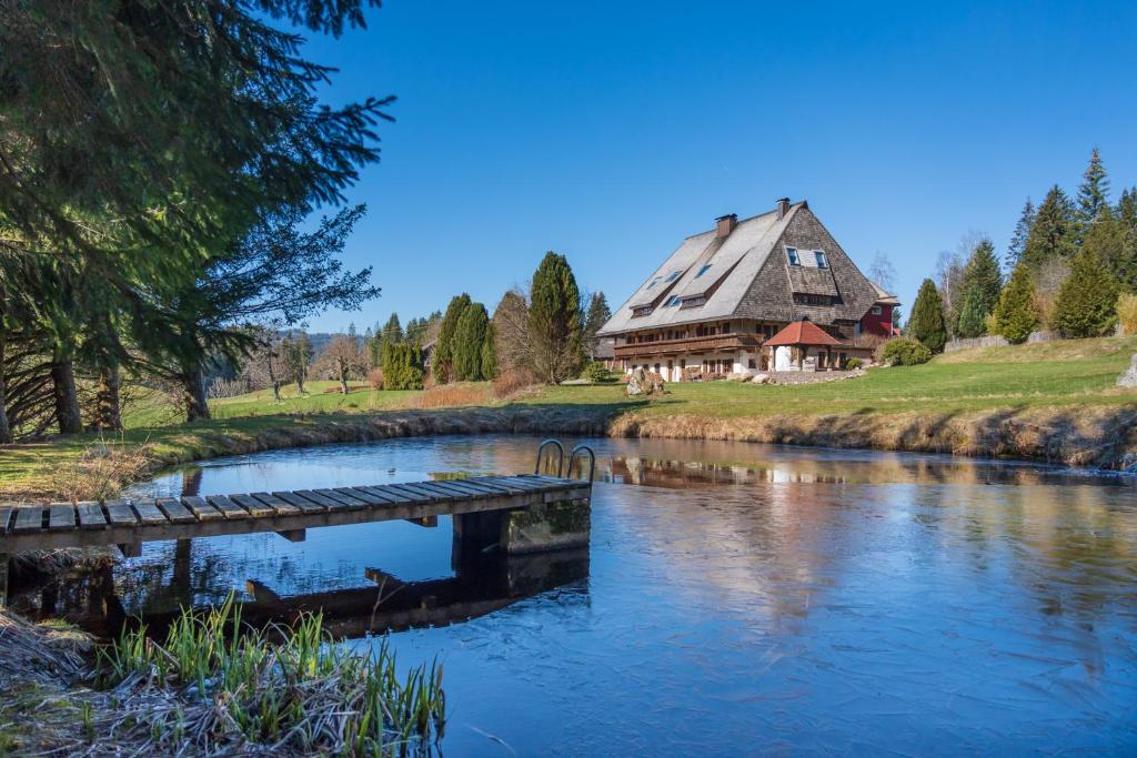 ein großes Haus neben einem Fluss mit einer Brücke in der Unterkunft Ferienwohnung im Hubertushof in Feldberg