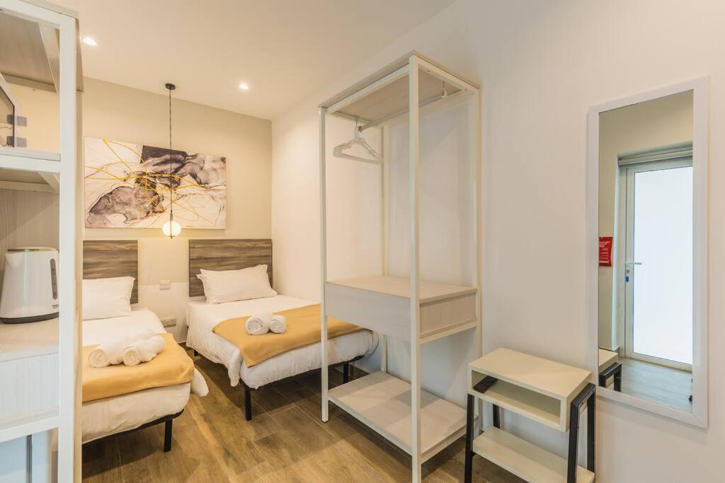 a small room with two beds and a mirror at Private studio 14 at the new OLO Living Guesthouse in Paceville