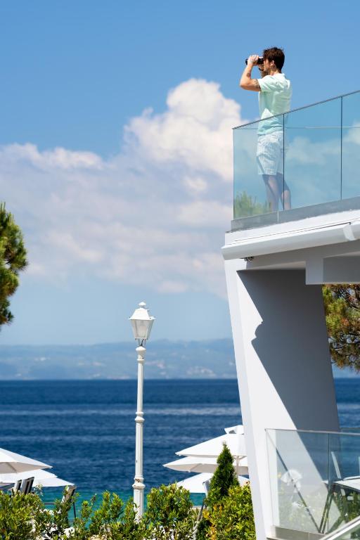 a woman on the balcony of a building with the ocean at Akti Toroni Boutique Hotel in Toroni