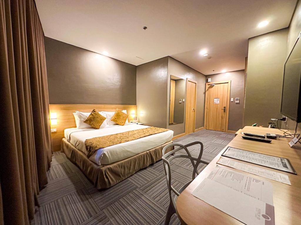 a hotel room with a bed and a desk at Madison 101 Hotel + Tower in Manila