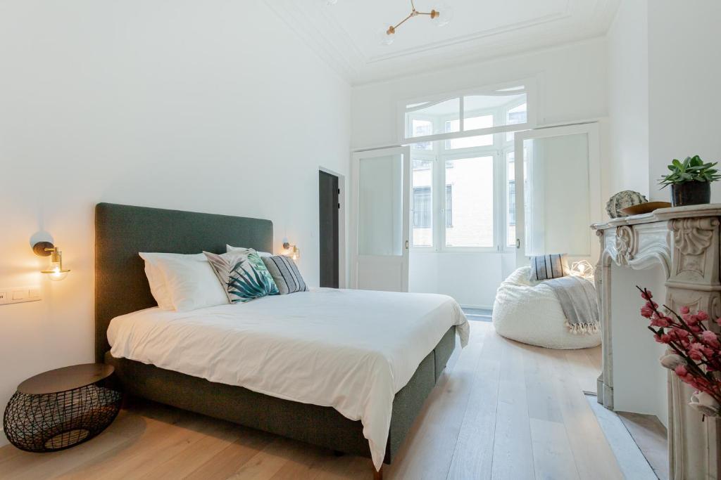 a white bedroom with a large bed and a window at RODELIJV in Ghent