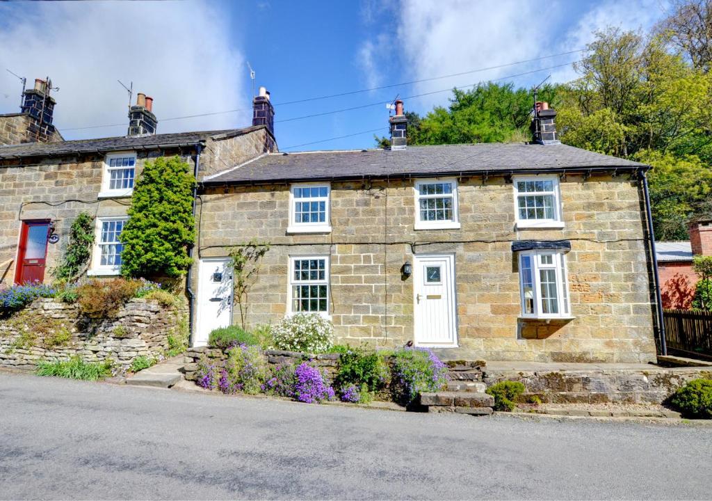an old stone house with white doors and windows at Hollins Cottage in Grosmont