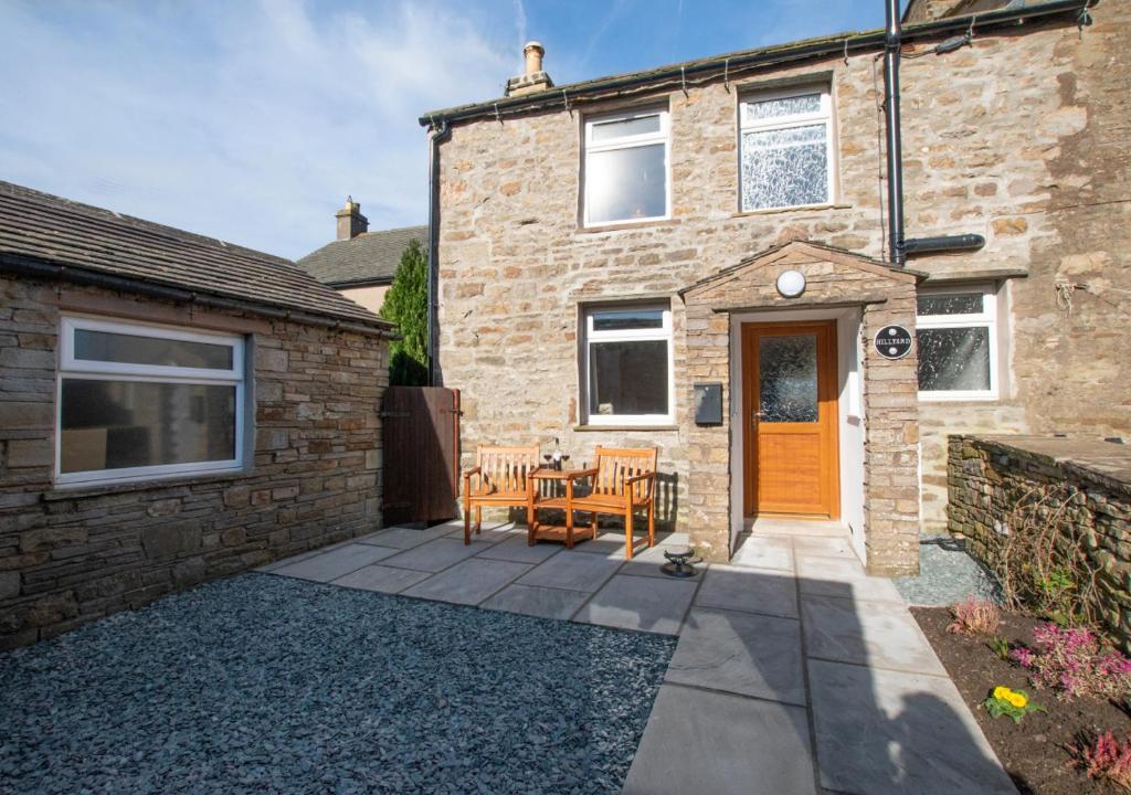 a brick house with a patio with a table and chairs at Hillyard in Hawes