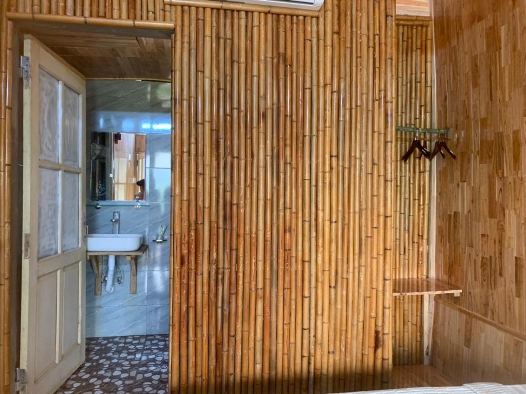 a bathroom with a bamboo wall with a sink at Green Homestay Mai Chau in Mai Chau