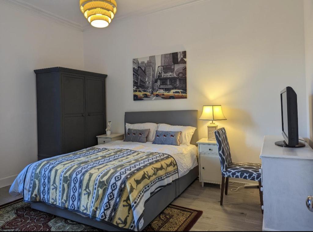 sypialnia z łóżkiem, biurkiem i telewizorem w obiekcie Bright Room Close to City Centre w Edynburgu