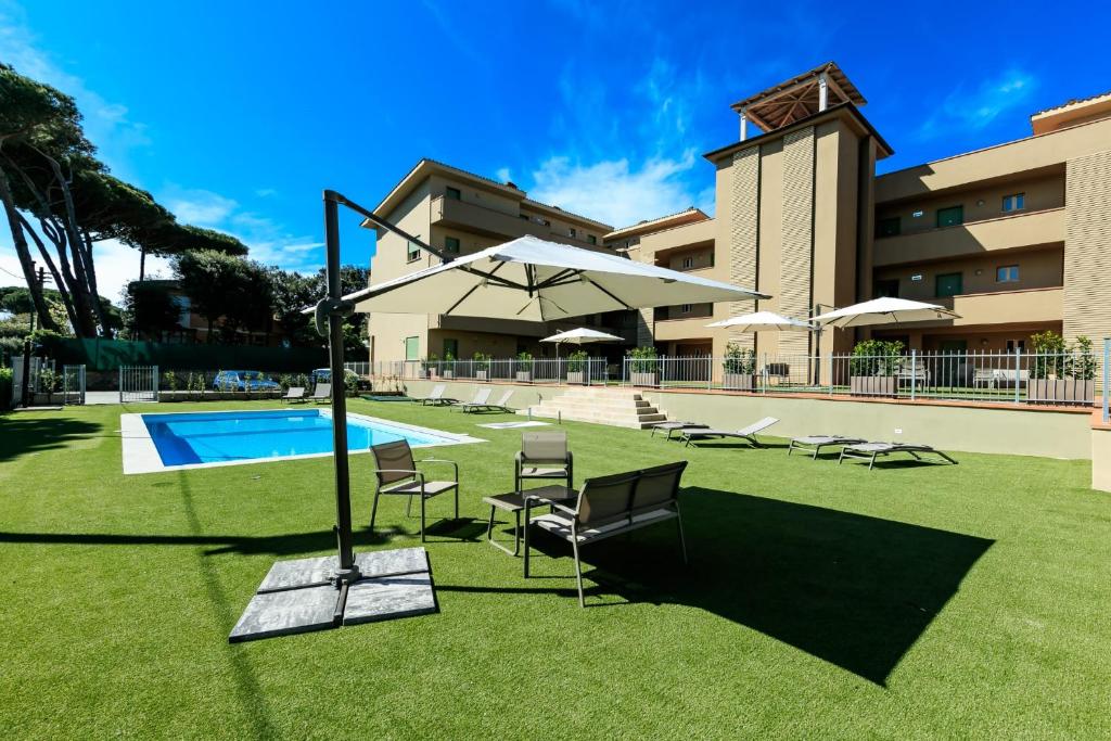 a pool with chairs and umbrellas in front of a building at Residence San Francesco in Tirrenia