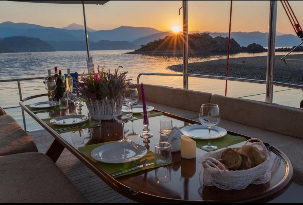 a table on a boat with wine glasses and the sunset at Aden Yatçılık in Bodrum City