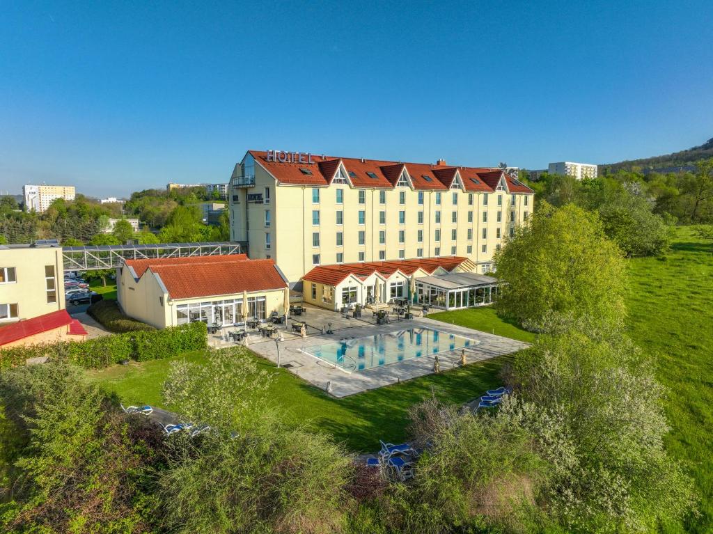 eine Luftansicht auf ein großes Gebäude mit einem Pool in der Unterkunft FAIR RESORT All Inclusive Wellness & Sport Hotel Jena in Jena