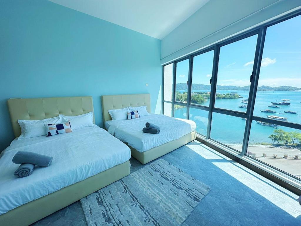 two beds in a room with a view of the ocean at Mari Mari Homestay - IMAGO THE LOFT in Kota Kinabalu