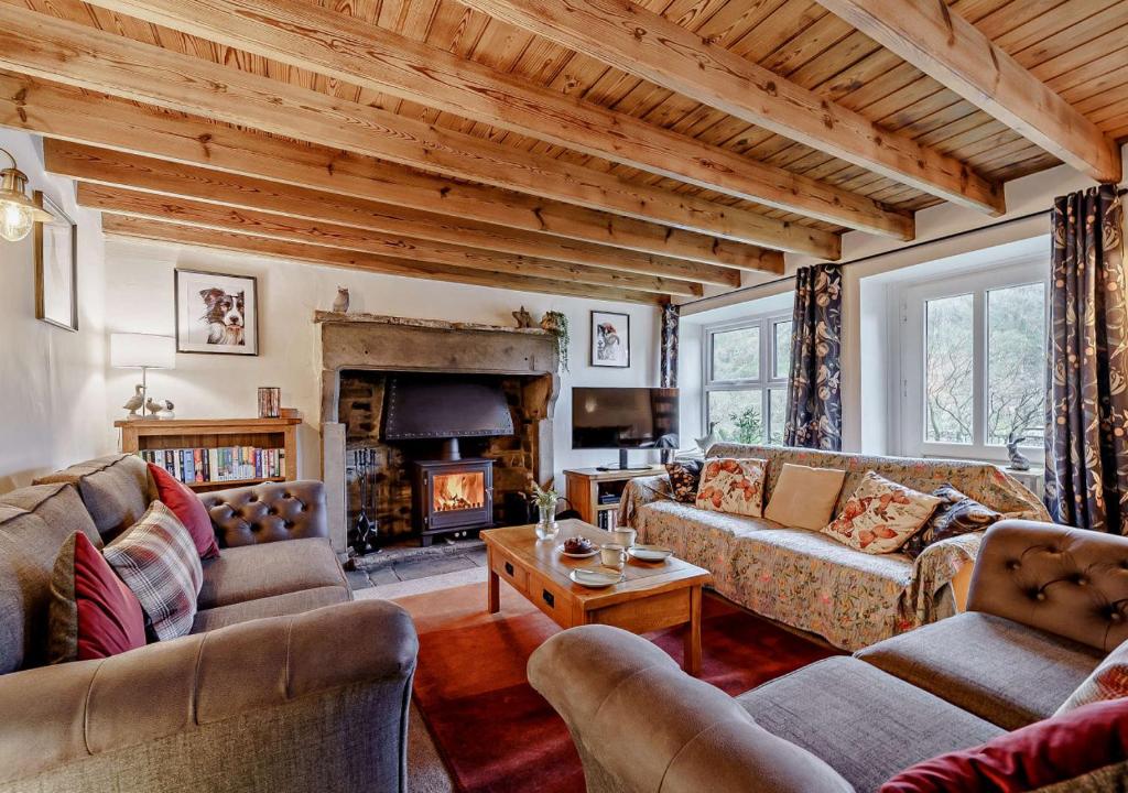 a living room with couches and a fireplace at High Green Cottage in Low Eskcleth