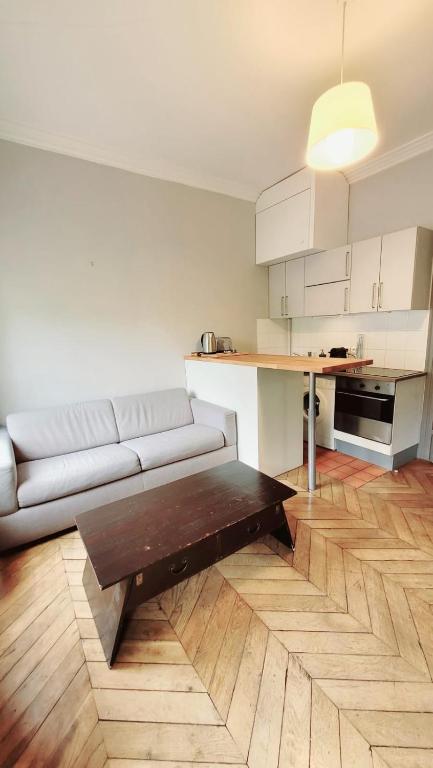 ein Wohnzimmer mit Sofa und Tisch in der Unterkunft Le Cyrano - Versailles in Versailles