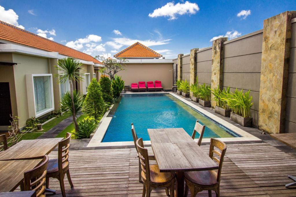 un patio trasero con piscina, mesa y sillas en Svarna Suites Seminyak, en Seminyak