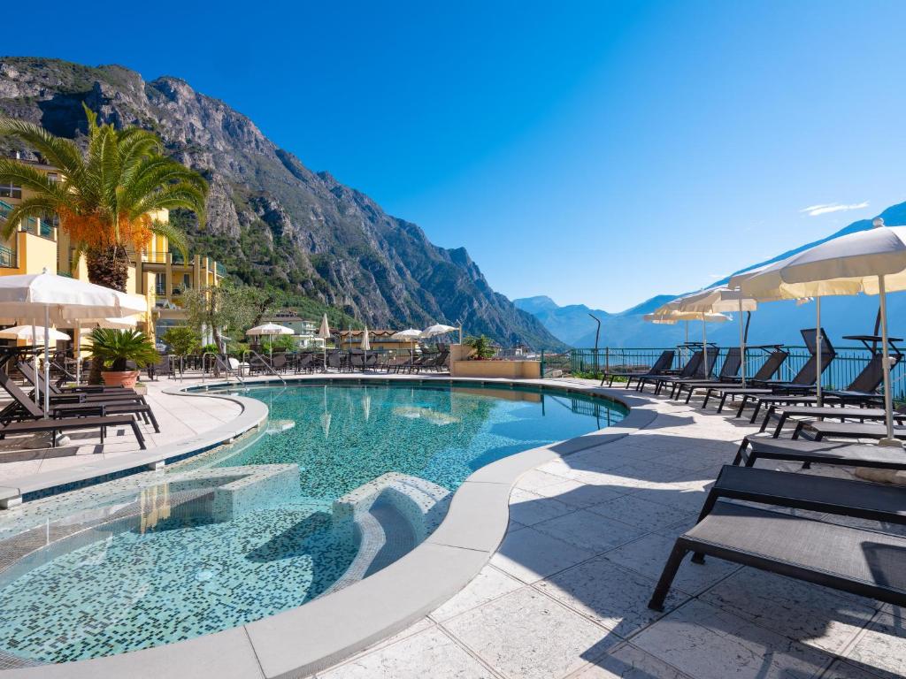 einen Pool mit Stühlen und Sonnenschirmen in einem Resort in der Unterkunft Hotel Cristina in Limone sul Garda