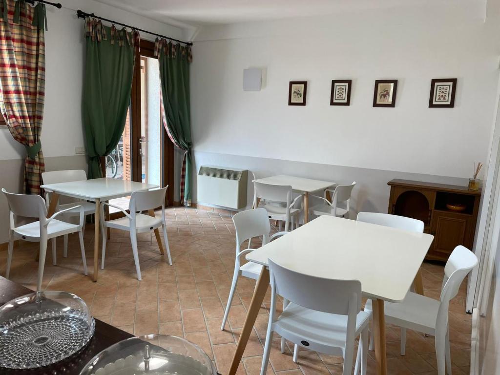 a dining room with white tables and white chairs at Villa del Colle Bevagna in Bevagna