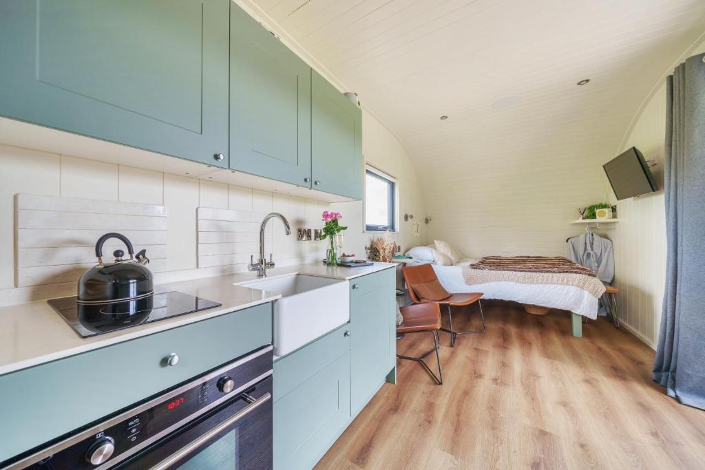 a kitchen with white cabinets and a bed in a room at Luna's Lookout in Cilcain