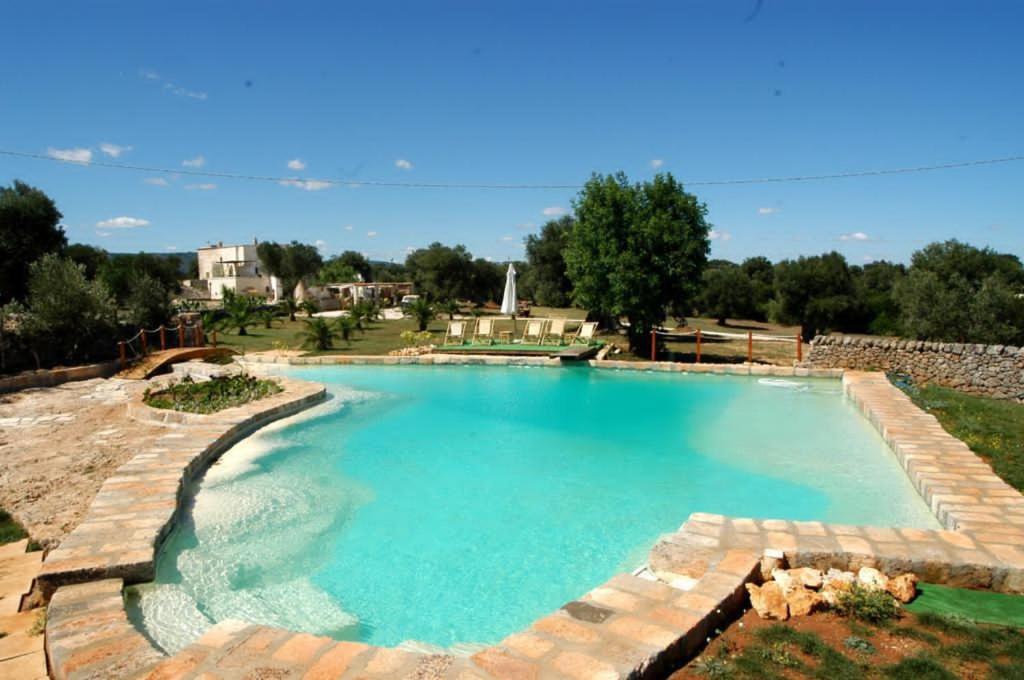 a large swimming pool with a stone wall around it at Masseria Piccole Taverne in Rosa Marina
