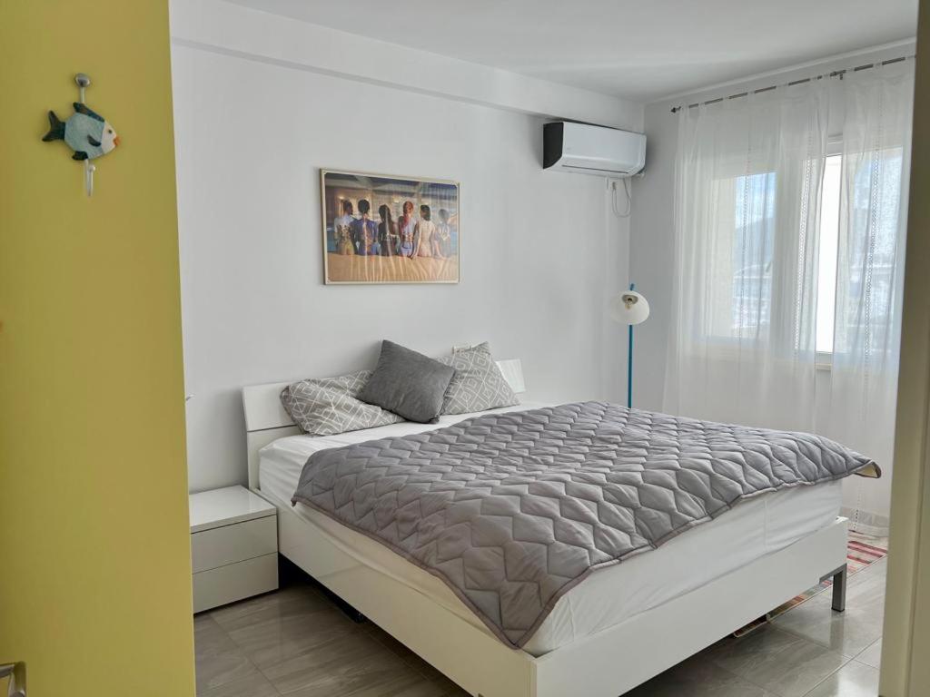 een witte slaapkamer met een groot bed en een raam bij White SideSea View Apartment in Sarandë