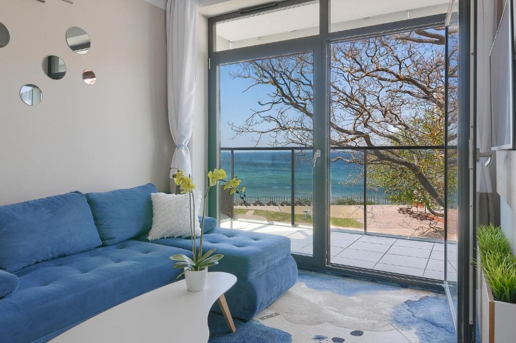 eine blaue Couch in einem Wohnzimmer mit Blick auf das Meer in der Unterkunft Apartament z widokiem na morze - Nadmorski Luksus Apartamenty in Ustronie Morskie