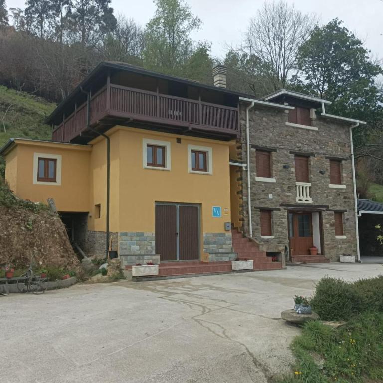 a large yellow house with a balcony at La Panera del Mejicano in Trevías