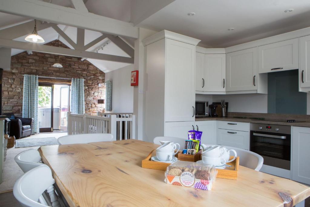 - une cuisine avec une table en bois et des placards blancs dans l'établissement Cloven Stone, Sebergham, Nr Caldbeck, à Sebergham