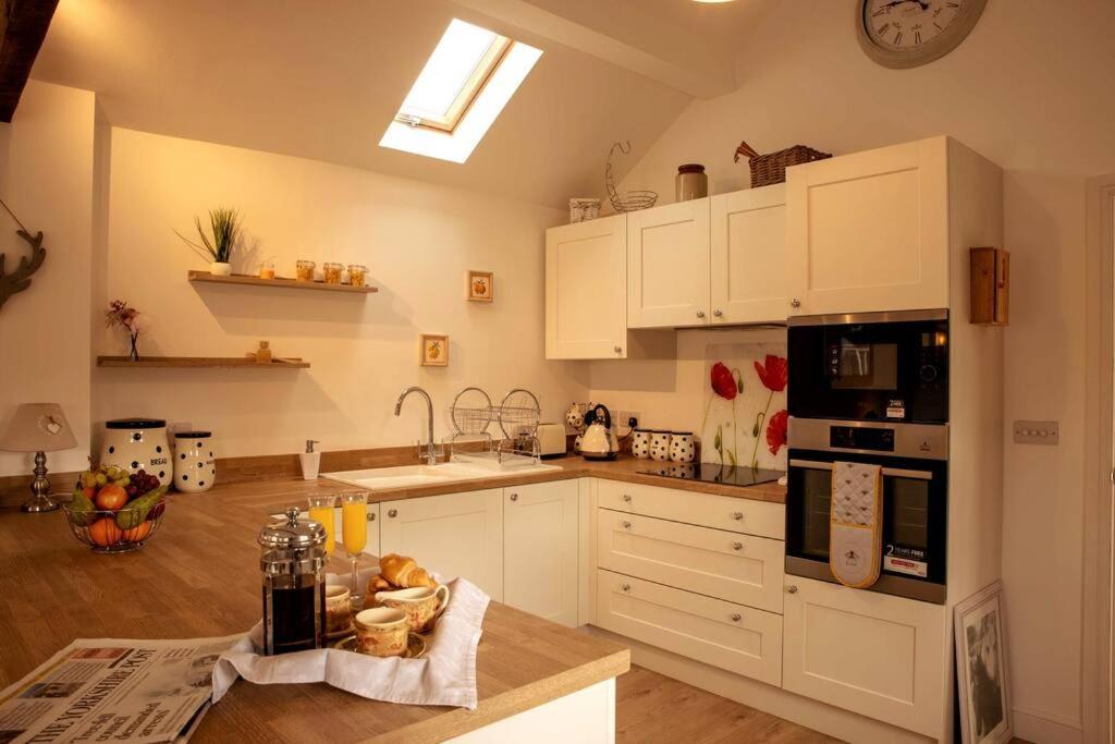 eine Küche mit weißen Schränken und einer Arbeitsplatte in der Unterkunft The Coach House - Raskelf - YO61 3LD 