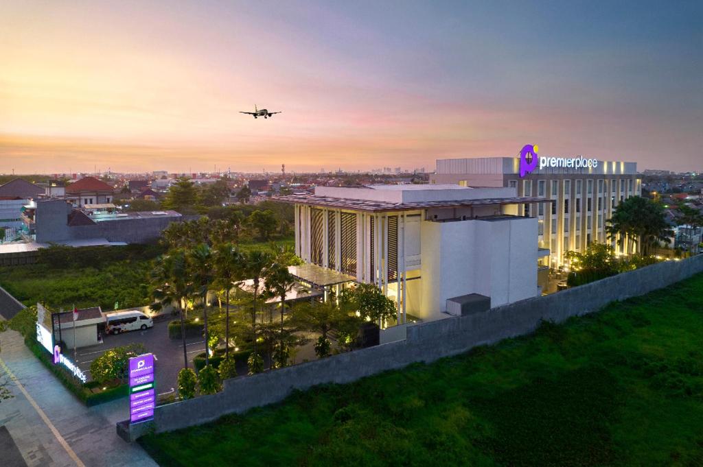 an airplane is flying over a building with a hotel at Premier Place Surabaya Airport in Sidoarjo