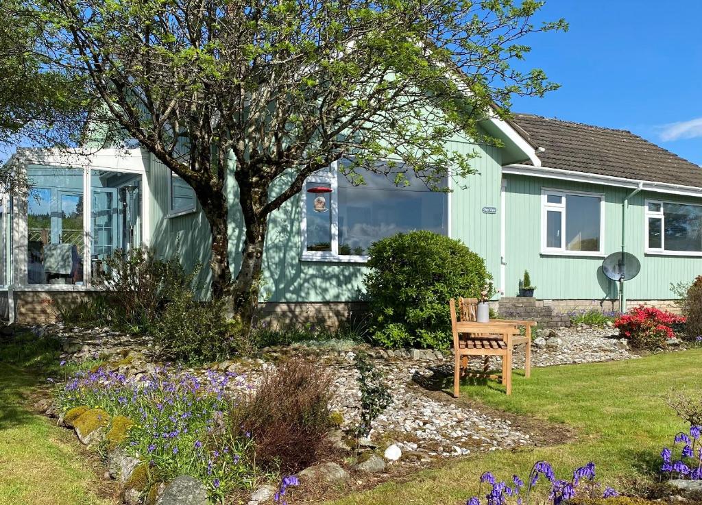 a house with a tree and flowers in the yard at Bay View in Lochgilphead