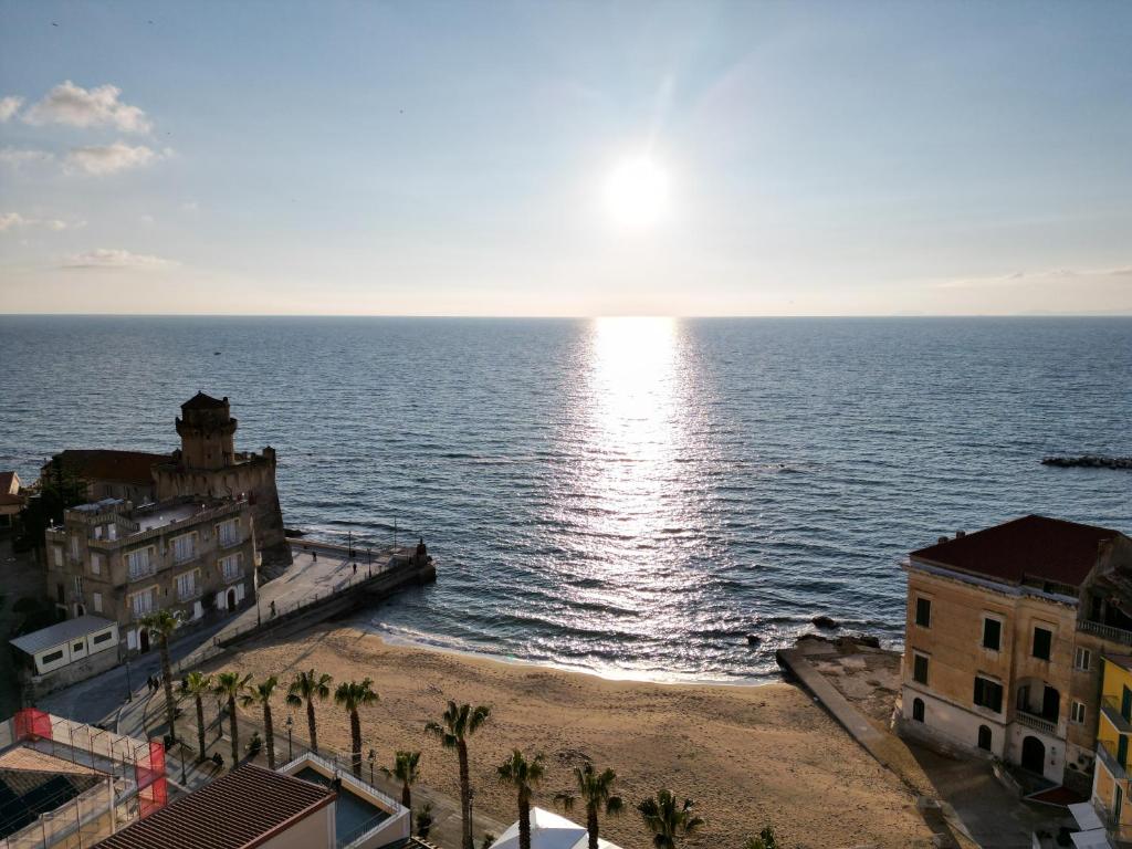 a view of the ocean with buildings and palm trees at Residenza d'epoca Olimpia in Santa Maria di Castellabate