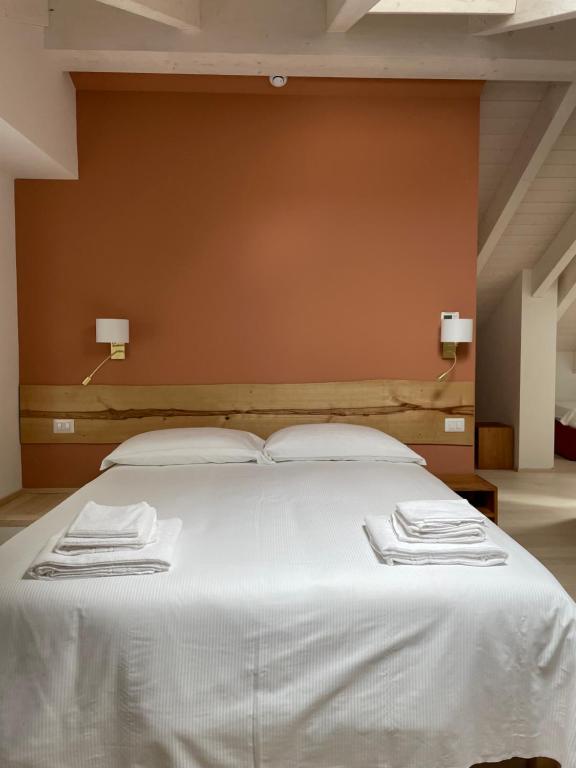 a large white bed with two white towels on it at Cascina Bagaggera in Rovagnate