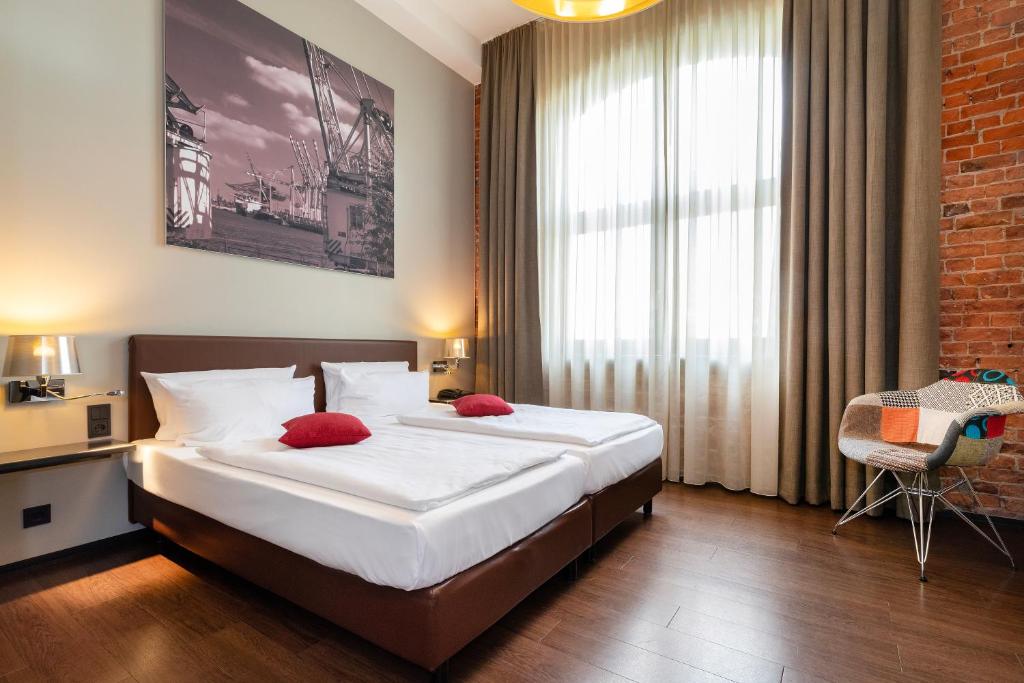 a bedroom with a large bed with red pillows at Hotel Volksschule in Hamburg