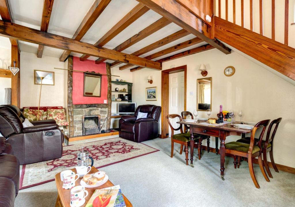 a living room with a table and chairs and a fireplace at East Cottage in Thwaite