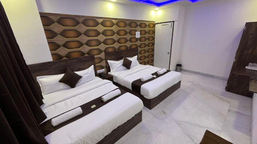 a bedroom with two beds and a wall at Hotel Plaza Rooms - Prabhadevi Dadar in Mumbai