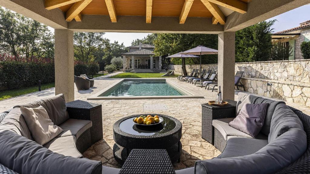 een patio met banken en een zwembad met een tafel bij Villa Mediterranean Retreat in Tinjan