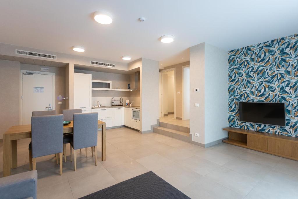 a kitchen and dining room with a table and a tv at Mosella Suite Hotel in Sottomarina
