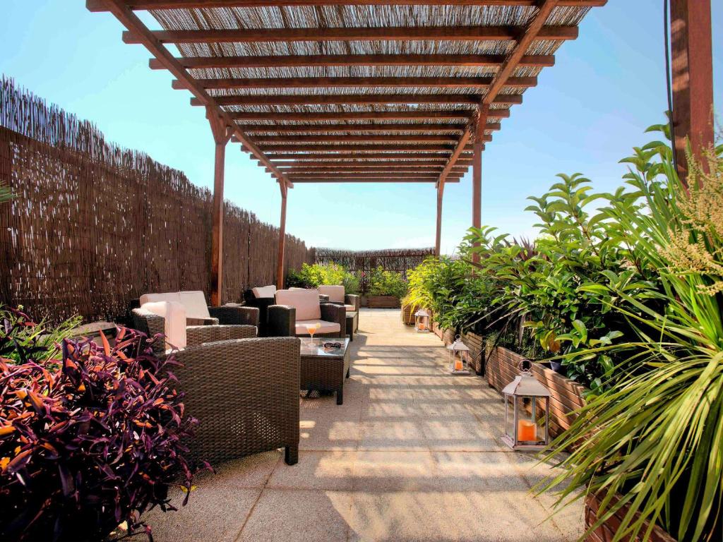 a patio with chairs and plants and a wooden pergola at Ibis Granada in Granada
