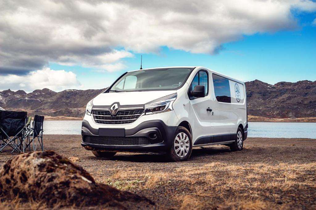 een wit busje geparkeerd in een veld naast een meer bij Rijo campers in Ytri-Njarðvík