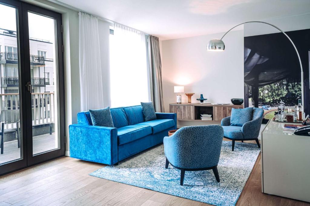 a living room with a blue couch and chairs at The Wellem, in The Unbound Collection by Hyatt in Düsseldorf