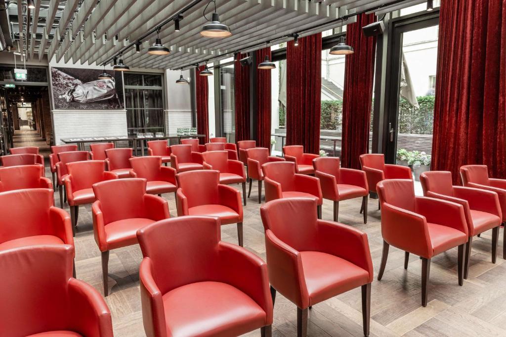 a row of red chairs in a room with windows at The Wellem, in The Unbound Collection by Hyatt in Düsseldorf