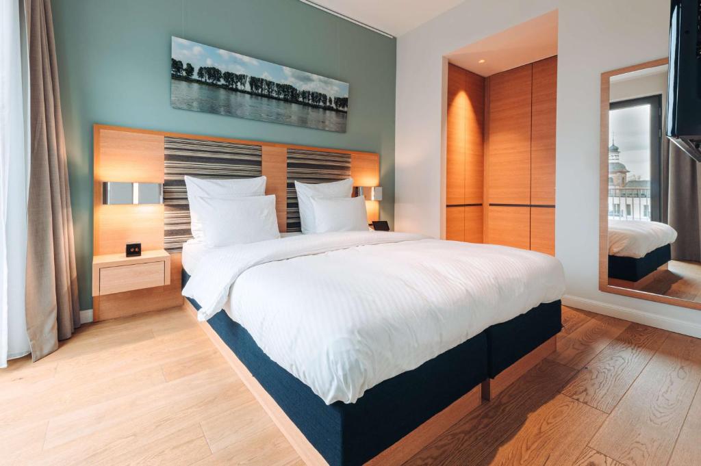 a bedroom with a large bed with white sheets at The Wellem, in The Unbound Collection by Hyatt in Düsseldorf
