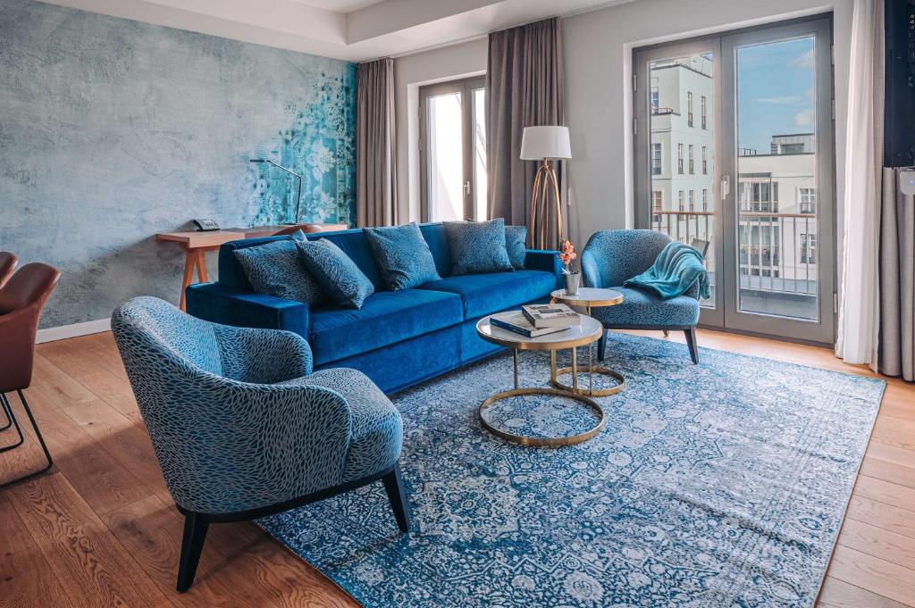 a living room with a blue couch and two chairs at The Wellem, in The Unbound Collection by Hyatt in Düsseldorf