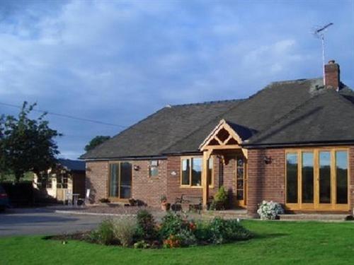 een groot bakstenen huis met een groot raam bij Dove Meadow in Denstone