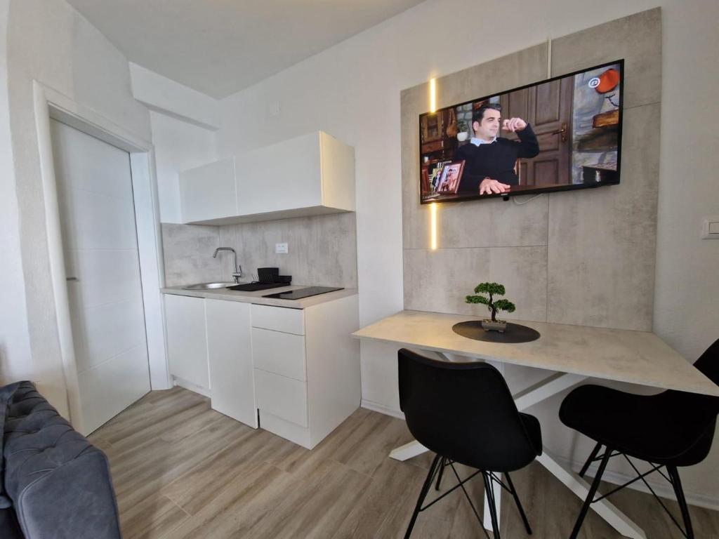 eine Küche mit einem Tisch und einem TV an der Wand in der Unterkunft Elegance Dream Apartment in Neum
